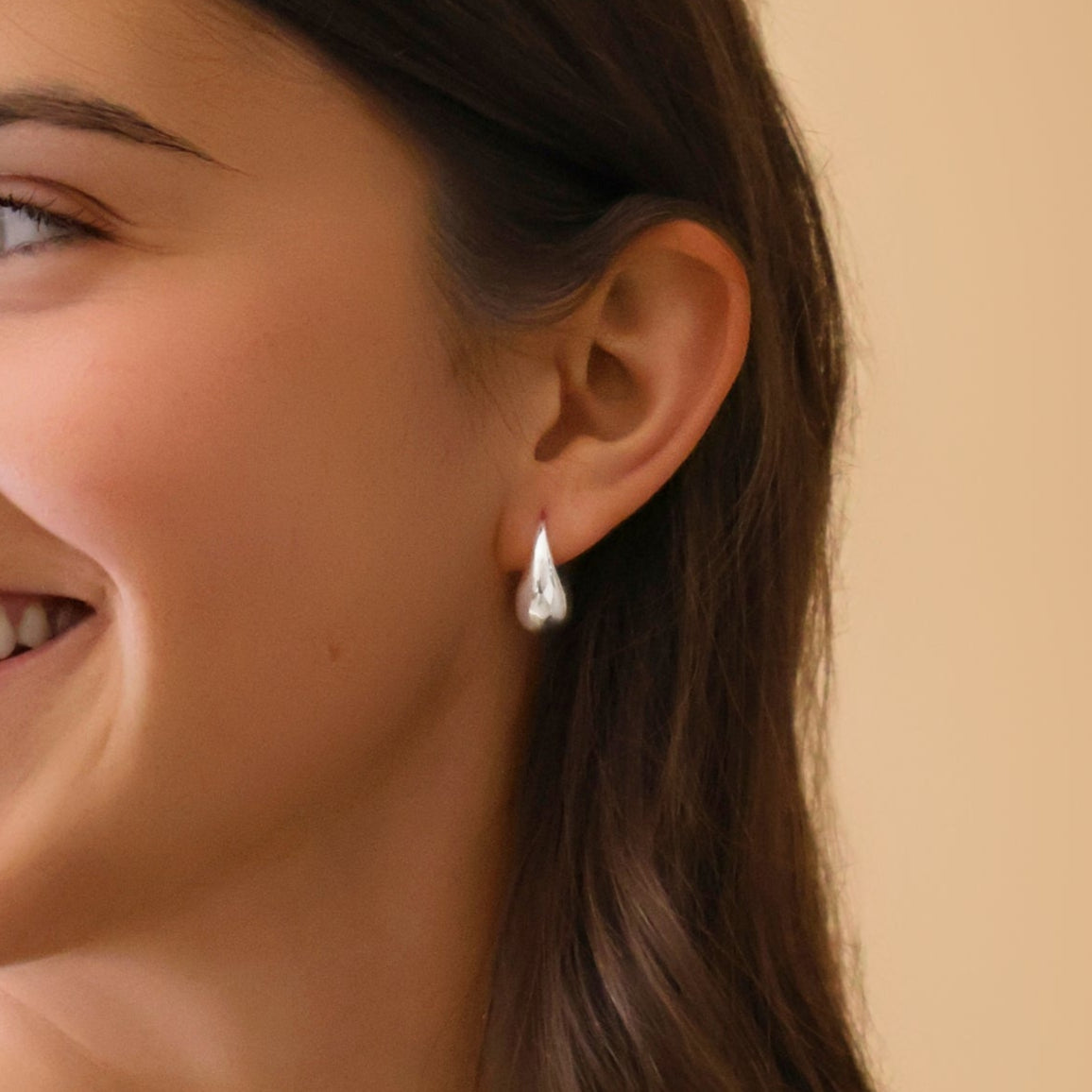 Woman wearing a white tank top and pearl necklace against a beige background